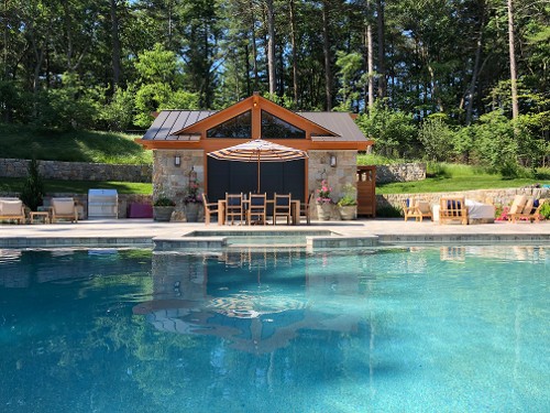 Stone veneered pool house and retaining walls atop travertine deck, infinity pool & built-in spa