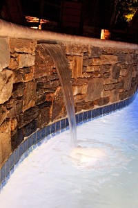 Stone pool veneer with fountain for classic elegance by New View, Inc.